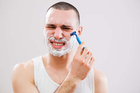 Young man cut himself while shaving his beard.の写真素材