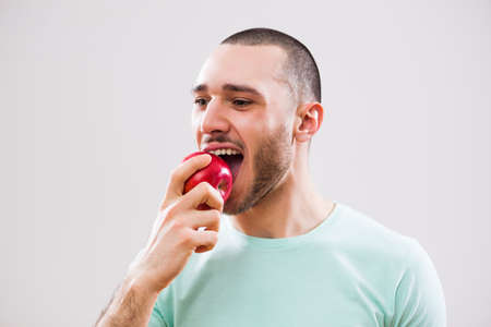 Young man is eating apple. Studio shot.の写真素材