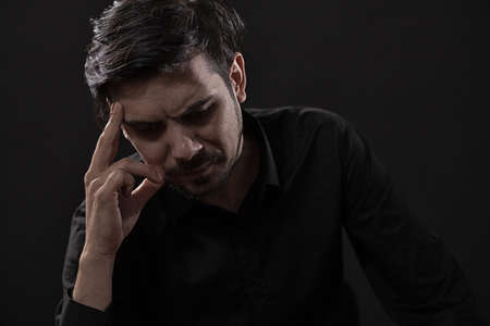 Portrait of pensive and worried adult man on black background.の写真素材