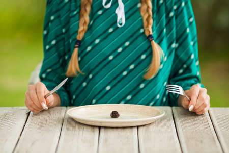 Young woman is having meager meal in times of scarcity.の写真素材