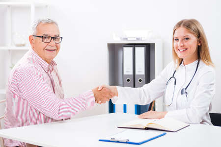 Happy patient is handshaking with his doctor after the successful treatment.の写真素材