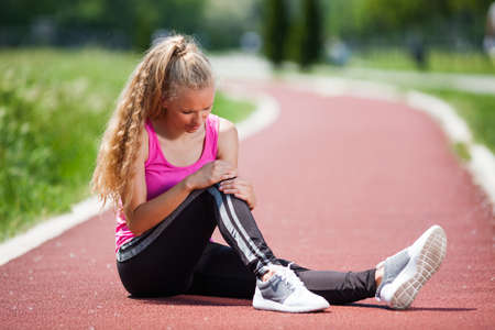 Young woman got injured while jogging on sunny day.の写真素材
