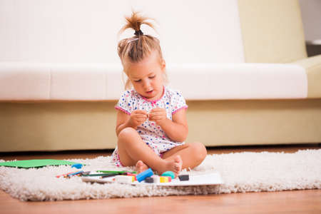 Little girl is playing with plasticine in home.の写真素材