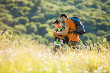 Father and son are hiking in nature in summer. They are looking at map.の写真素材