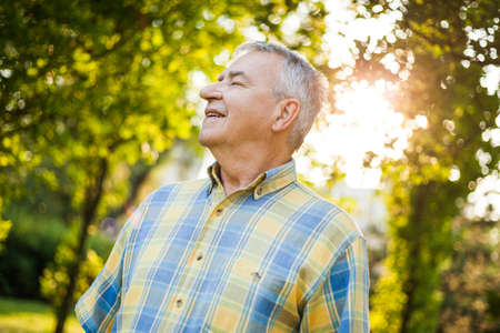 Happy senior man is enjoying fresh air in nature.の写真素材