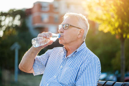 Outdoor portrait of senior man who is drinking water.の写真素材