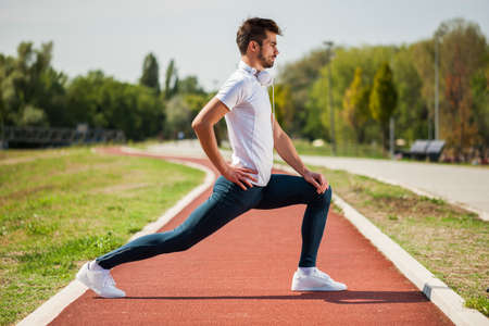 Young man is exercising on sunny day. He is stretching his body.の写真素材