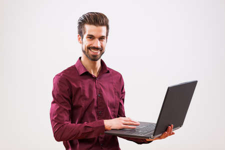 Studio shot portrait of young successful businessman who is using laptop.の写真素材