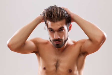 Young man is applying hair gel to his hair.の写真素材