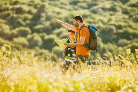 Father and son are hiking in nature in summer. They are looking at map.の写真素材