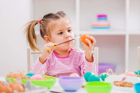 Little girl is coloring eggs for Easter.の写真素材