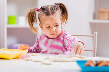 Little girl is playing and making cookies in kitchen.の写真素材