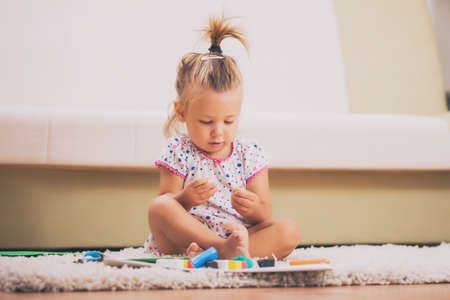 Little girl is playing with child's play clay in home.の写真素材