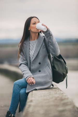 Young woman is drinking coffee to go after work.の写真素材