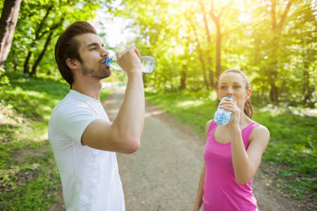 Young couple exercising in park. They are drinking water.の写真素材