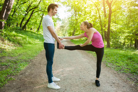 Couple is exercising in park. They are stretching bodies.の写真素材