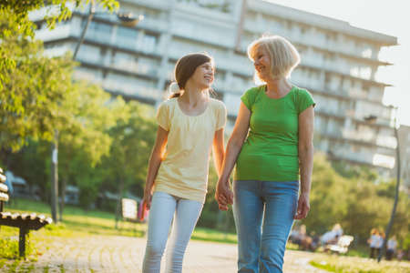 Grandmother and granddaughter are walking in park in summer.の写真素材