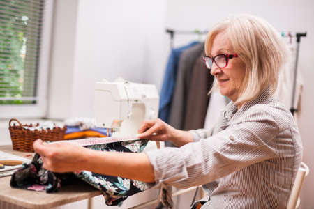 Adult woman is sewing in her studio.の写真素材