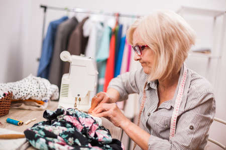 Adult woman is sewing in her studio.の写真素材