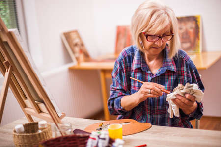 Elderly woman is painting in her home. Retirement hobby.の写真素材