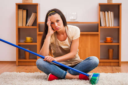 Young woman has to clean the house. She is lazy.の写真素材