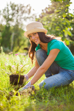 Young happy woman is planting a flower in her garden.の写真素材
