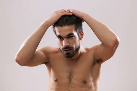 Young man is applying hair gel to his hair.の写真素材