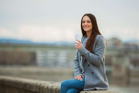 Young woman is drinking coffee to go after work.