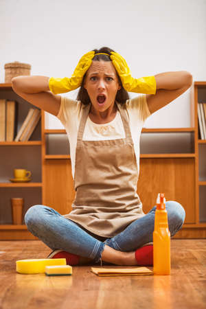 Young woman has to clean the house. She is lazy and frustrated.の写真素材