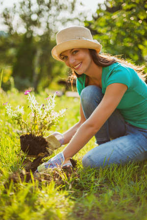 Young happy woman is planting a flower in her garden.の写真素材