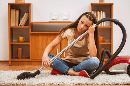 Young woman has to clean the house. She is lazy.の写真素材