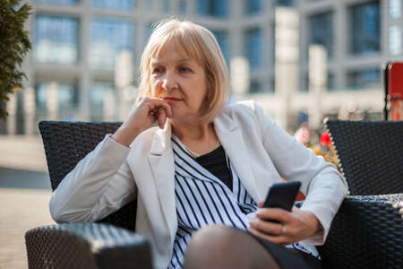 Senior businesswoman is sitting in cafe and searching for job on internet.の写真素材