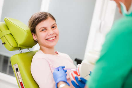 Dentist is teaching little girl about oral hygiene.の写真素材