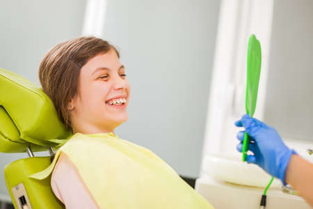 Little girl is looking at her teeth at dentist.の写真素材