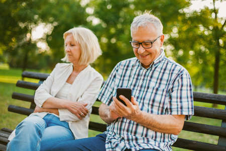 Senior woman is angry while her man is messaging on phone.の写真素材