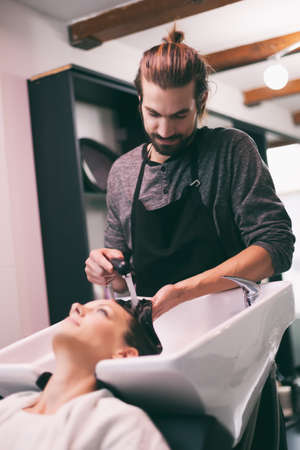 Young woman getting new hairstyle at professional hair styling saloon.の写真素材