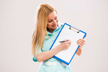 Portrait of young doctor who is holding clipboard and showing document with pen.の写真素材