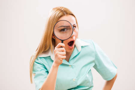 Young excited nurse looking through loupe.の写真素材