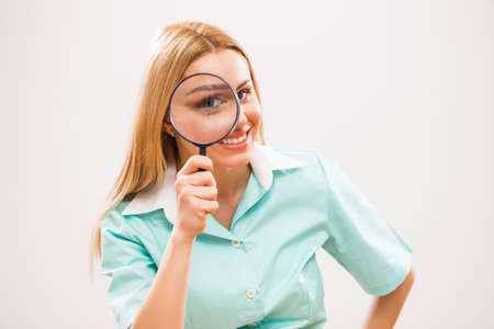 Young excited nurse looking through loupe.の写真素材