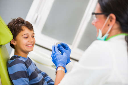Dentist is teaching little boy about braces.の写真素材
