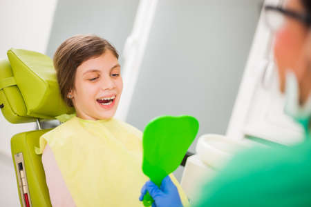 Little girl is looking at her teeth at dentistの写真素材