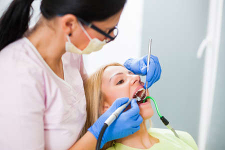 Young woman at dentist. Dentist is repairing her teeth.の写真素材