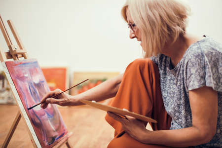 Elderly woman is painting in her home. Retirement hobby.の写真素材