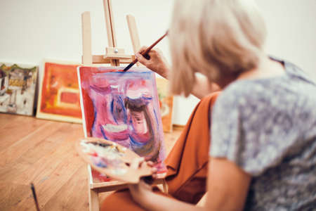 Elderly woman is painting in her home. Retirement hobby.の写真素材