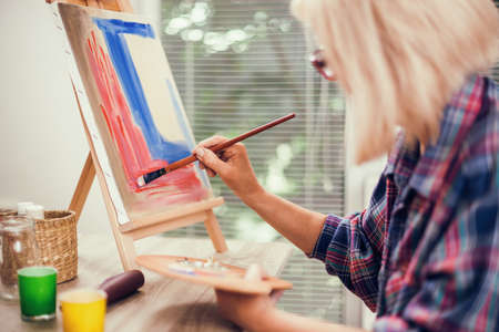 Elderly woman is painting in her home. Retirement hobby.の写真素材