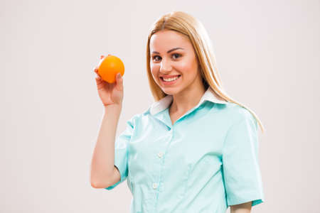 Portrait of young nurse who is holding orange.の写真素材