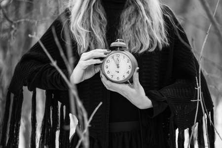Close up image of woman holding vintage clock that shows five to twelve time.の写真素材