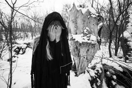 Depressed and lonely woman covering her face in forest in winter.の写真素材