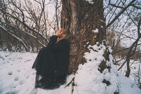 Depressed and lonely woman crying in forest in winter.の写真素材