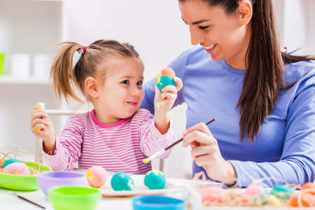 Happy mother and daughter coloring eggs for Easter.の写真素材